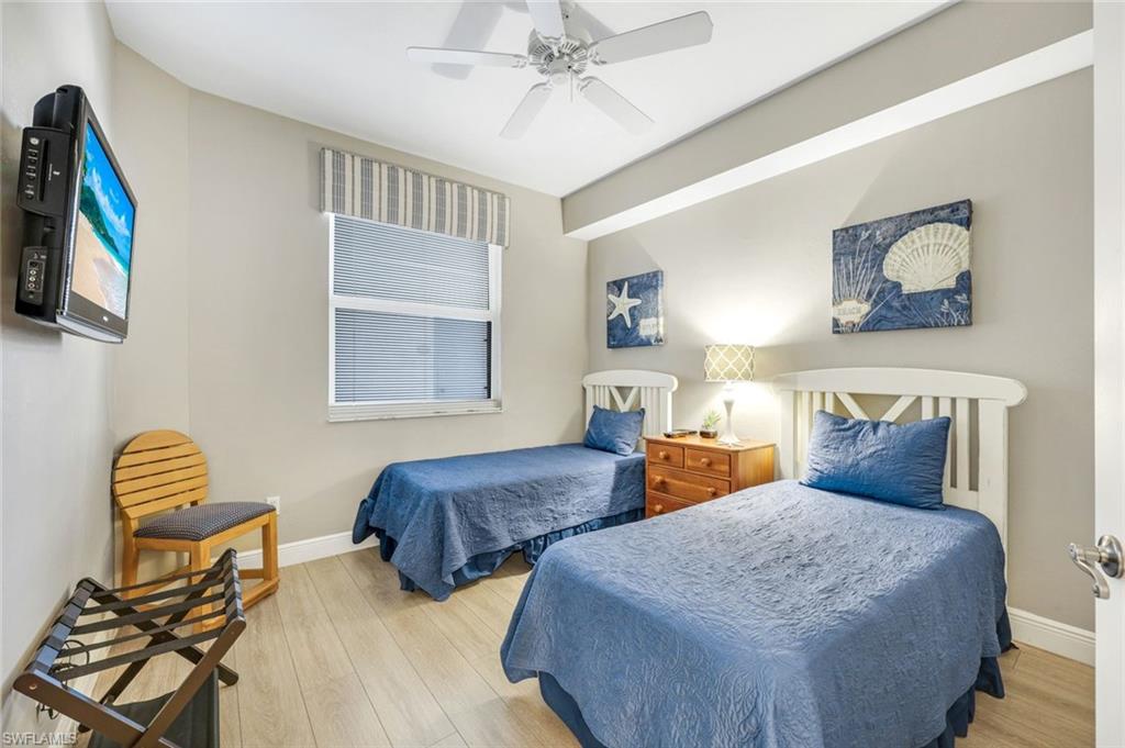 470 Launch Circle, Unit 403 Naples, FL 34108 - Photo 13 of 25 a bedroom with two beds and a chandelier
