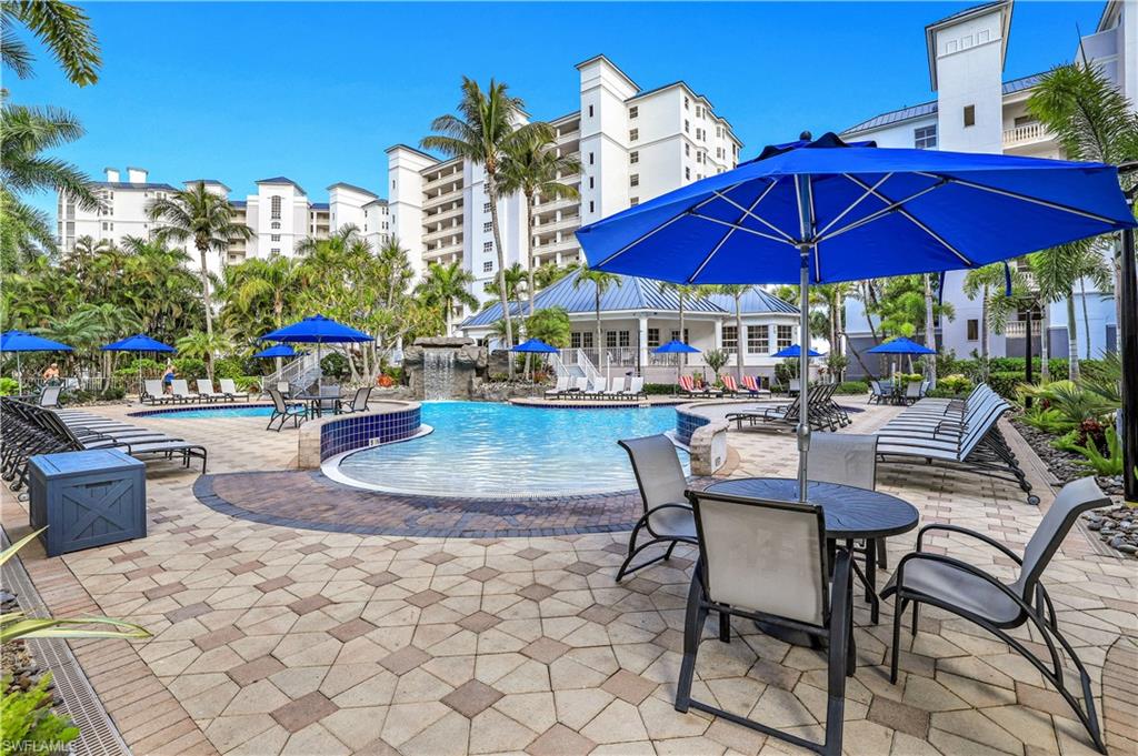 470 Launch Circle, Unit 403 Naples, FL 34108 - Photo 19 of 32 a patio with tables and chairs and a umbrella