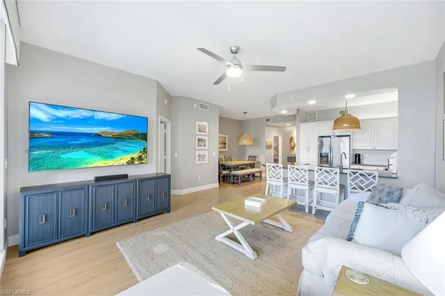 a living room with furniture a flat screen tv and kitchen view