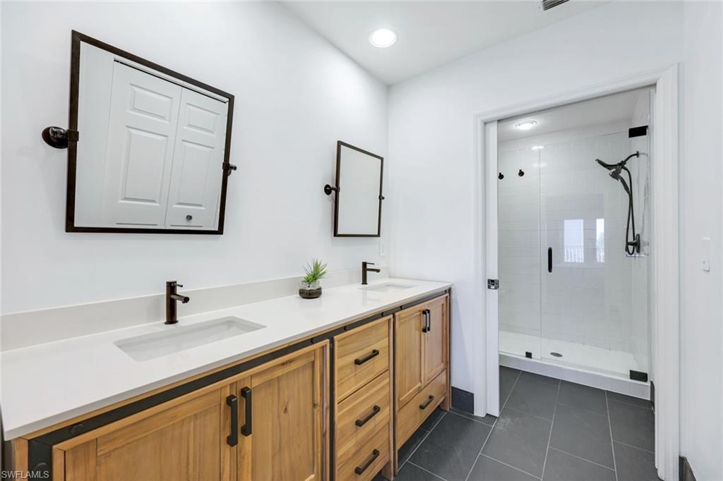 470 Launch Circle, Unit 403 Naples, FL 34108 - Photo 10 of 25 a bathroom with a double vanity sink and mirror