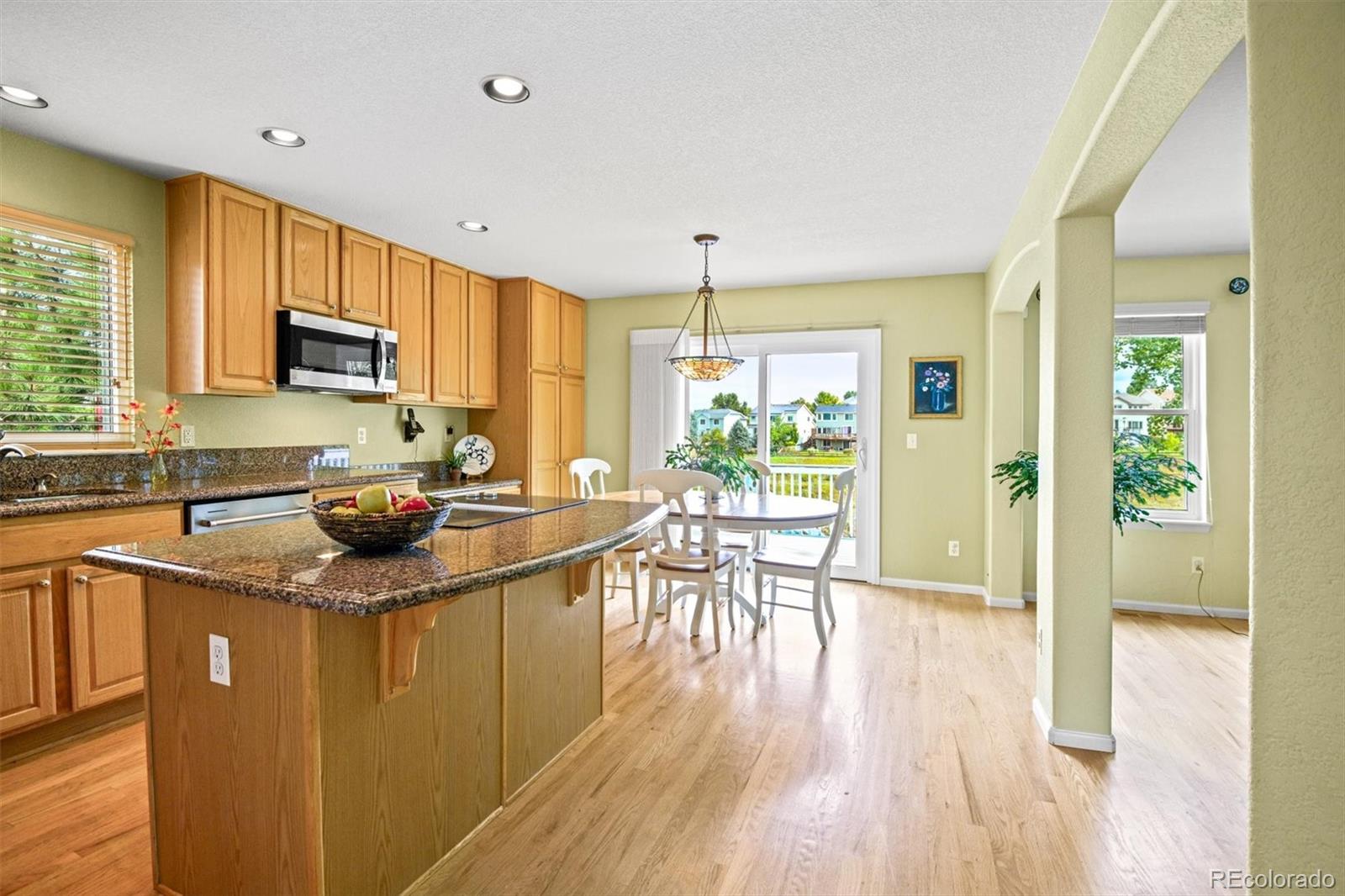 10230 Rustic Redwood Way Highlands Ranch, CO 80126 - Photo 16 of 50 a kitchen with stainless steel appliances granite countertop a stove top oven a sink dishwasher and a refrigerator with wooden floor