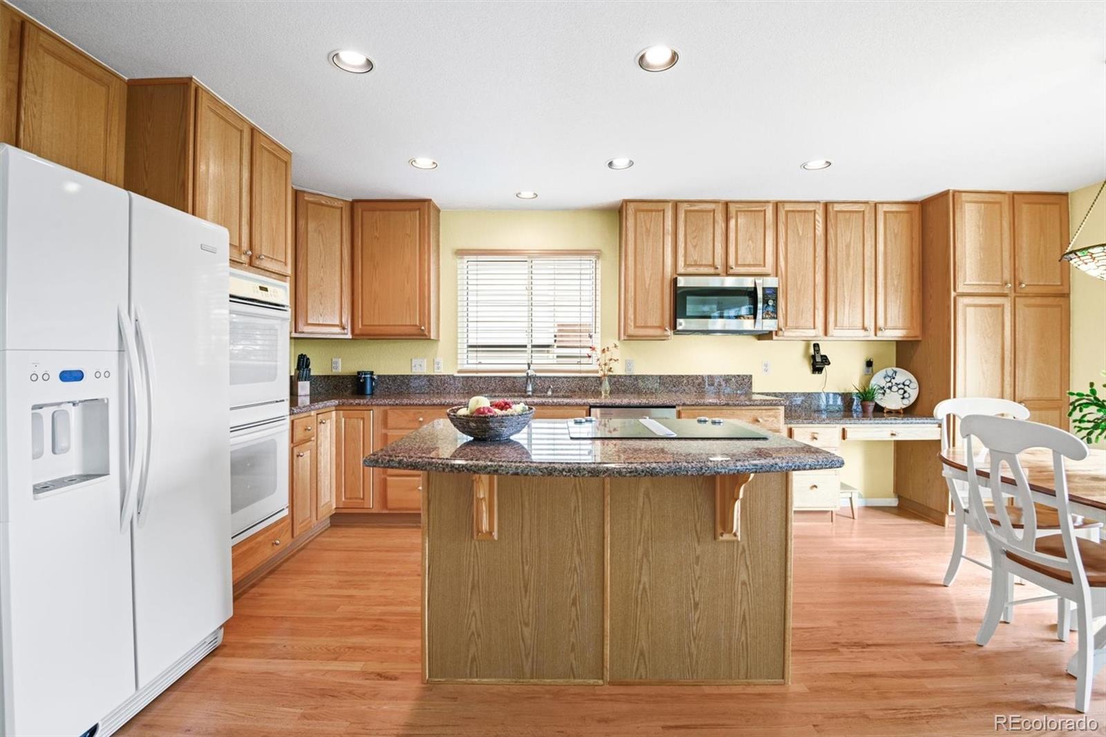 10230 Rustic Redwood Way Highlands Ranch, CO 80126 - Photo 17 of 50 a kitchen with stainless steel appliances granite countertop a refrigerator a sink dishwasher a stove and white countertops with wooden floor