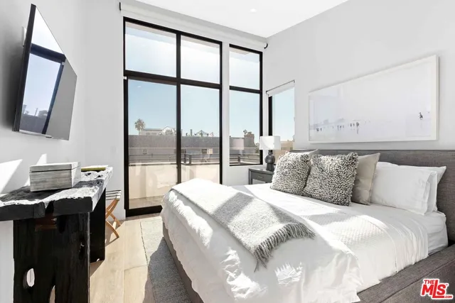 a bedroom with a large bed and a flat tv screen on dresser