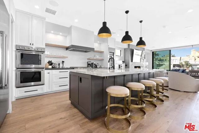 a kitchen with stainless steel appliances granite countertop a stove a sink a microwave a dining table and chairs with wooden floor