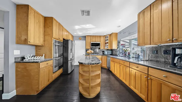 a kitchen with stainless steel appliances granite countertop a stove a sink and a refrigerator