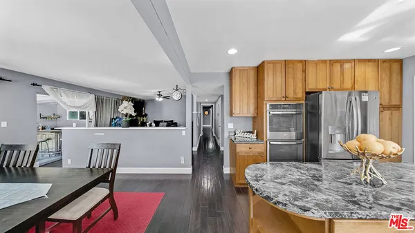 a living room with stainless steel appliances granite countertop furniture and wooden floor