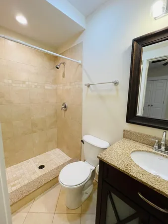 a bathroom with a granite countertop sink toilet a mirror and shower