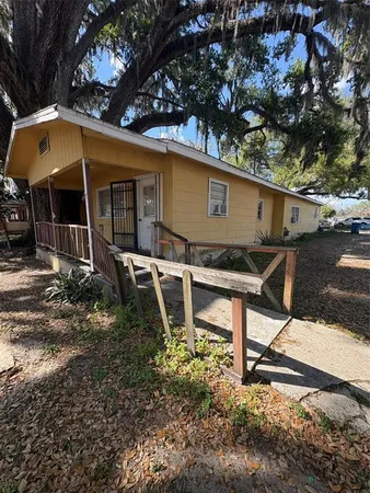 a backyard of a house with table and chairs under an umbrella