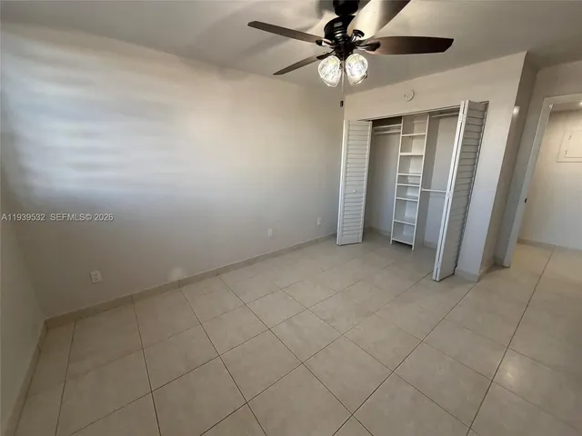 an empty room with a ceiling fan and carpet