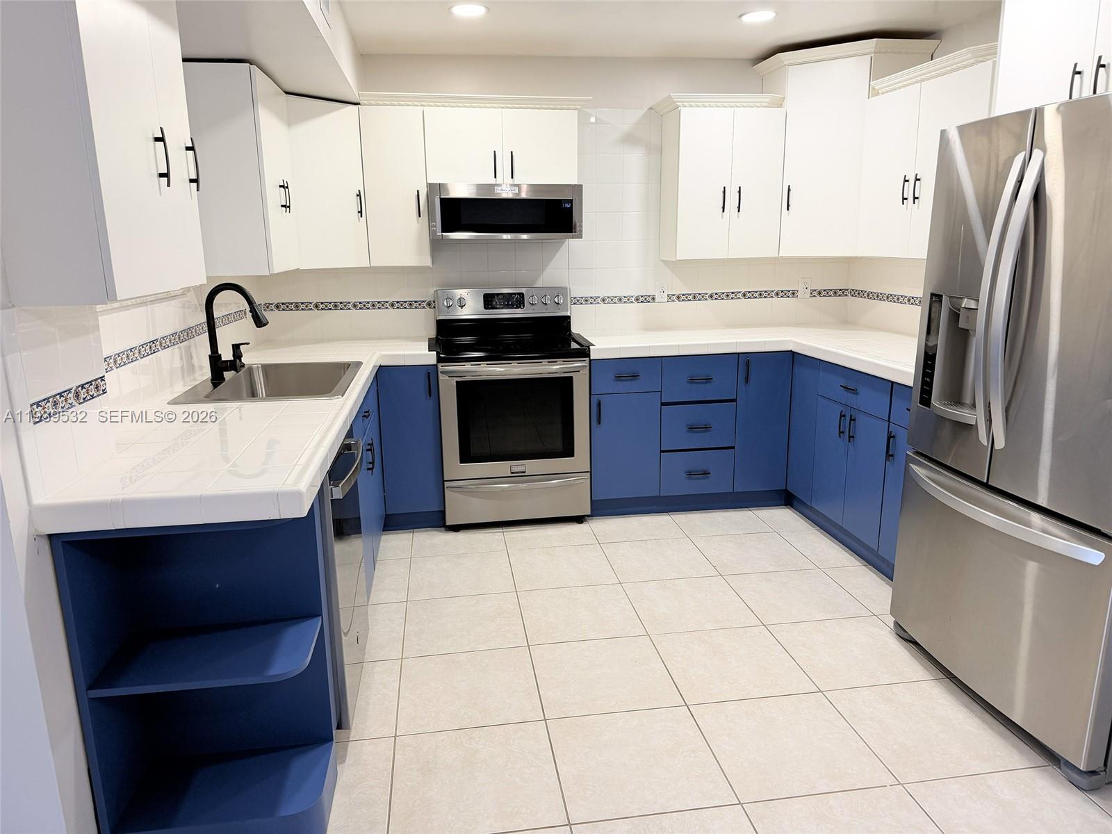 11755 Southwest 18th Street, Unit 109 Miami, FL 33175 - Photo 3 of 21 a kitchen with stainless steel appliances a sink a stove a microwave and cabinets