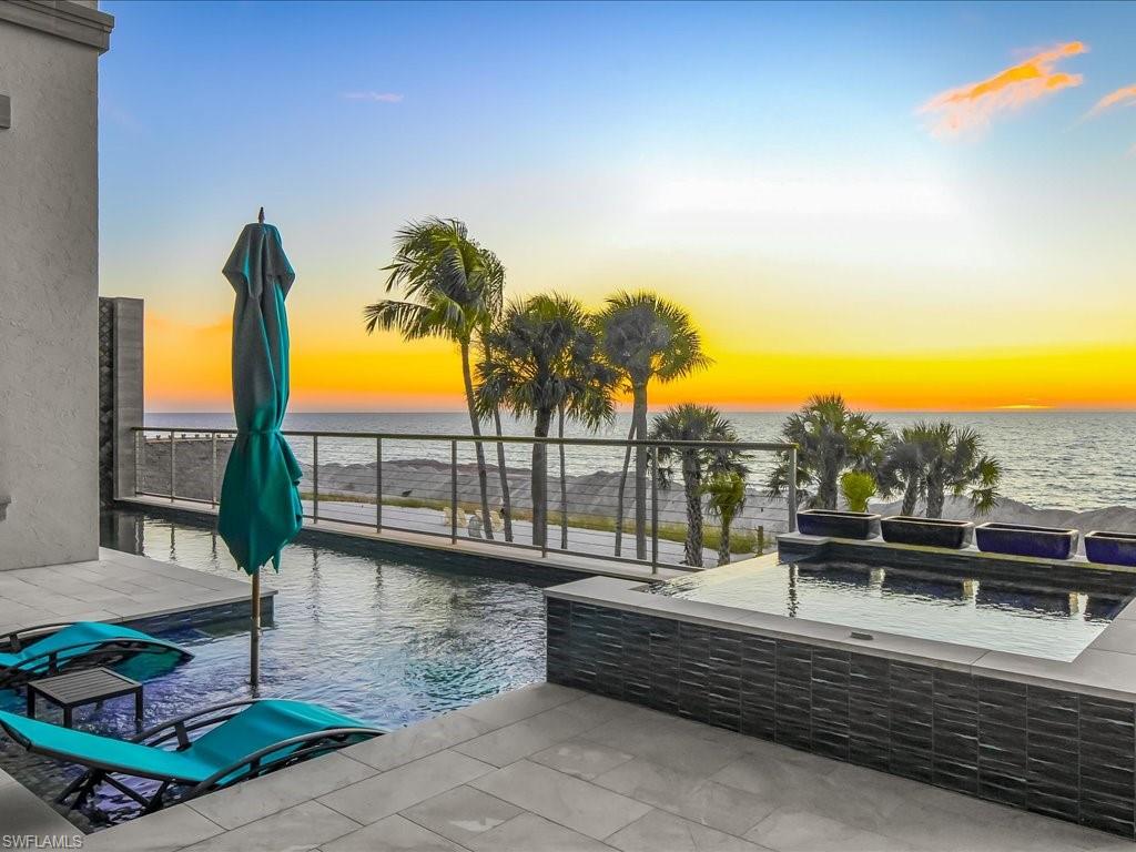 7409 Bay Colony Drive Naples, FL 34108 - Photo 12 of 48 a view of a swimming pool with a patio and ocean view