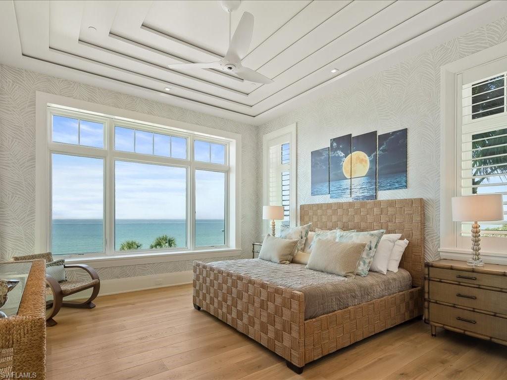 7409 Bay Colony Drive Naples, FL 34108 - Photo 15 of 46 Bedroom with wallpapered walls, a water view, and hardwood / wood-style floors