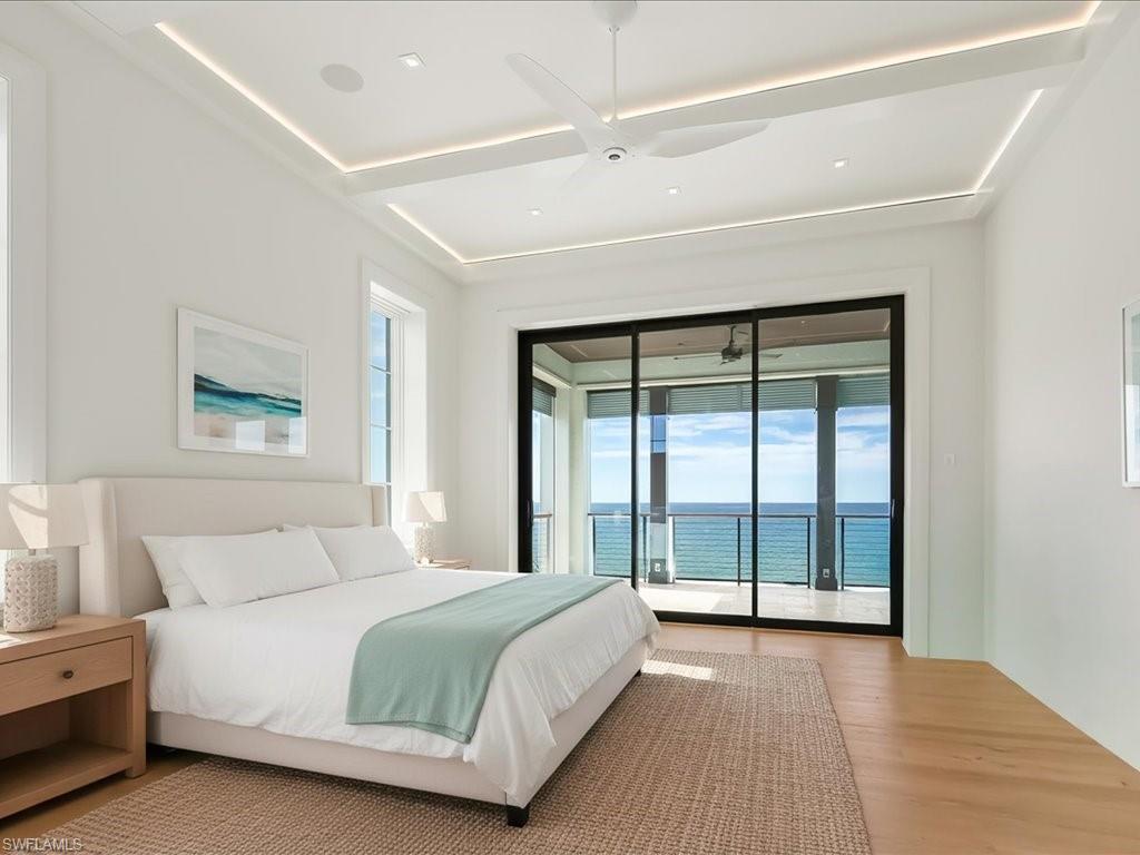 7409 Bay Colony Drive Naples, FL 34108 - Photo 17 of 46 Bedroom with a water view, access to outside, wood finished floors, and a ceiling fan