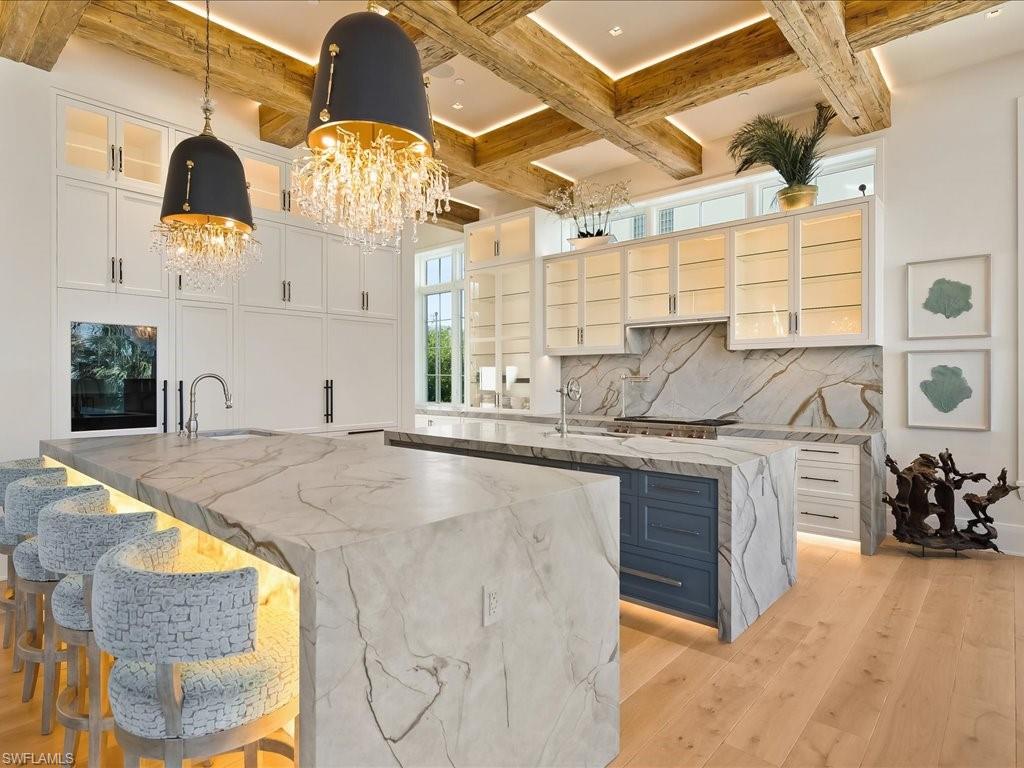 7409 Bay Colony Drive Naples, FL 34108 - Photo 3 of 46 Kitchen with a breakfast bar area, light stone countertops, light wood-style floors, hanging light fixtures, and white cabinets