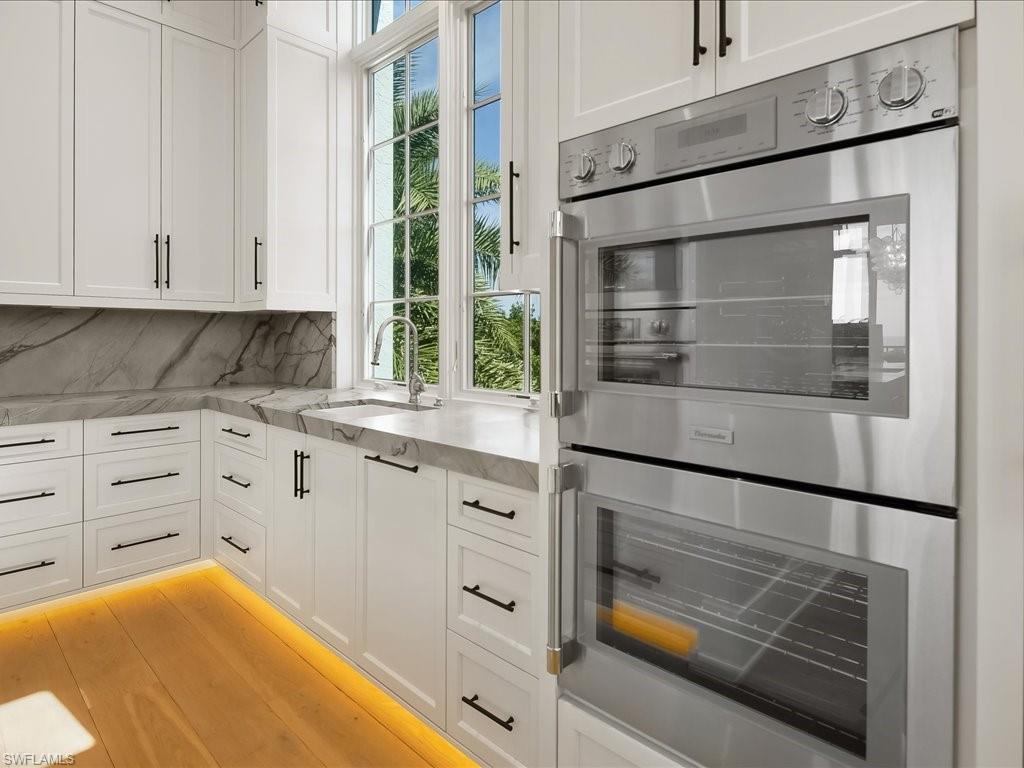 7409 Bay Colony Drive Naples, FL 34108 - Photo 31 of 48 a kitchen with white cabinets and a window