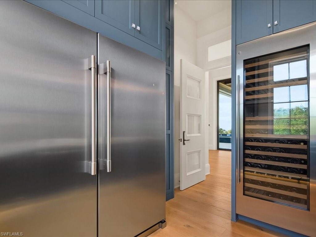 7409 Bay Colony Drive Naples, FL 34108 - Photo 35 of 46 Kitchen featuring beverage cooler, built in fridge, blue cabinets, and light wood-style flooring