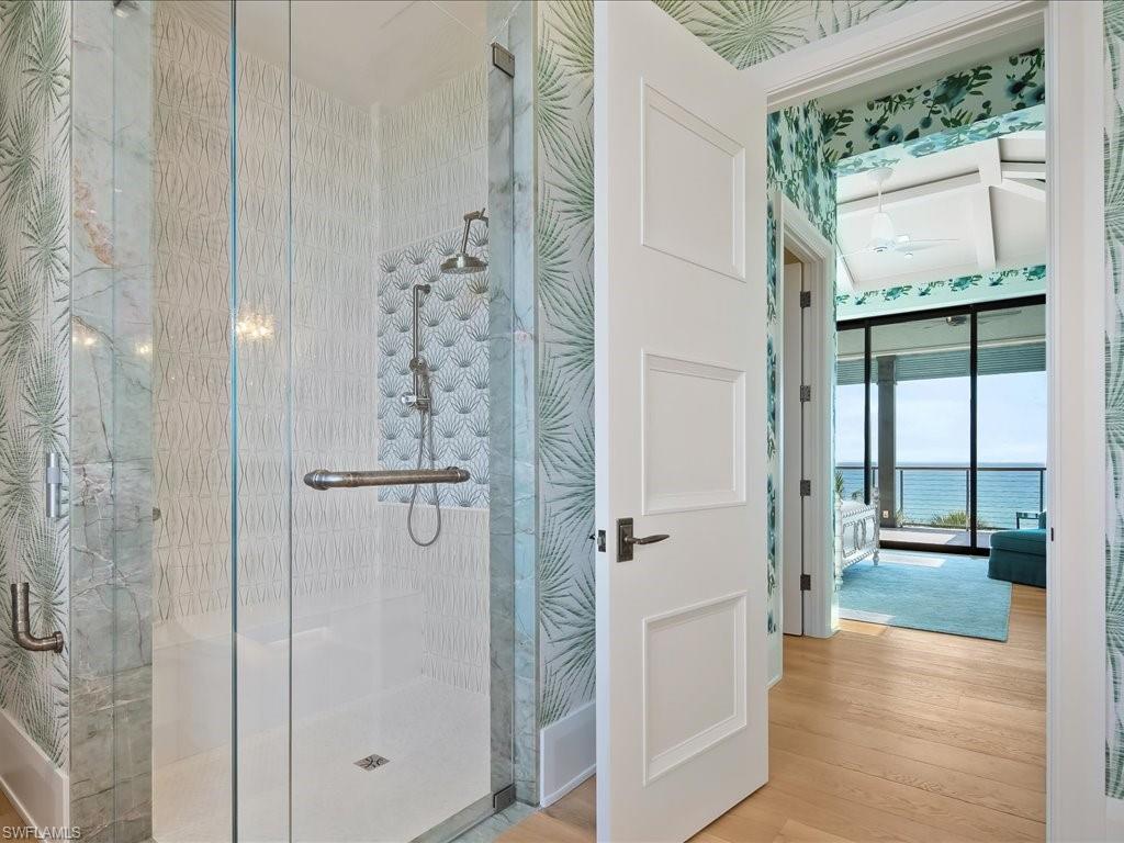 7409 Bay Colony Drive Naples, FL 34108 - Photo 40 of 46 Full bathroom with a shower stall, wood finished floors, a ceiling fan, and wallpapered walls