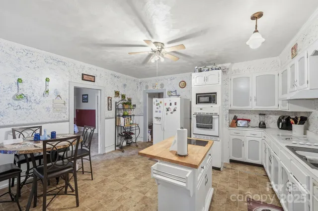 a kitchen with stainless steel appliances granite countertop a stove top oven a sink a dining table and chairs with white cabinets