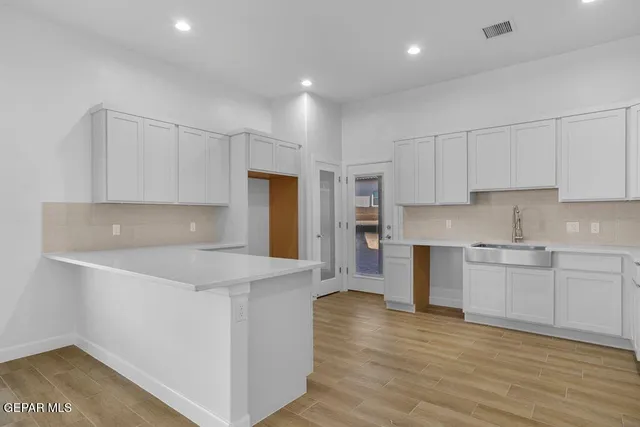 a kitchen with kitchen island a sink white cabinets and stainless steel appliances