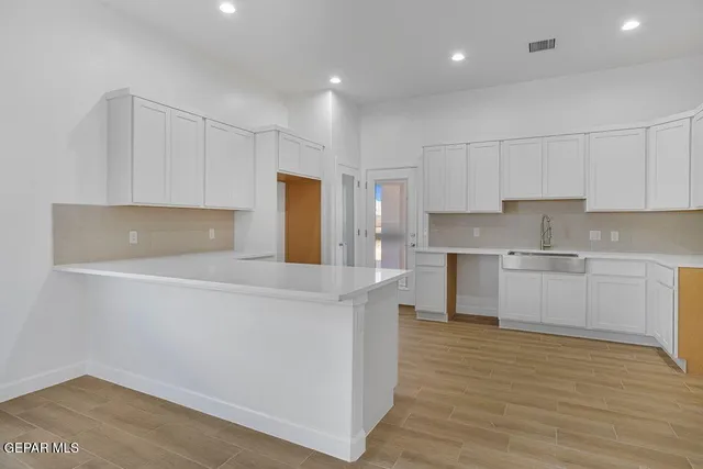a kitchen with stainless steel appliances white cabinets and wooden floor