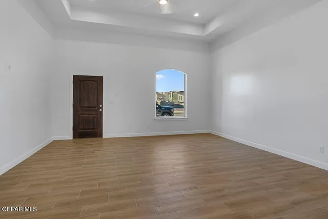 a view of an empty room with wooden floor and a window