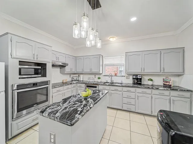 a kitchen with stainless steel appliances granite countertop a stove top oven a sink dishwasher a dining table and chairs with white cabinets