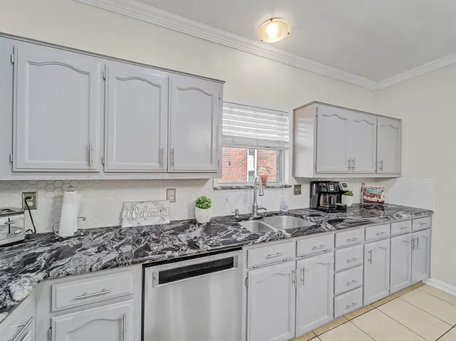 a kitchen with stainless steel appliances granite countertop white cabinets sink and window