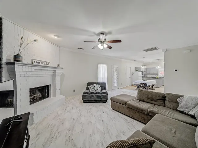 a living room with furniture a fireplace and a ceiling fan