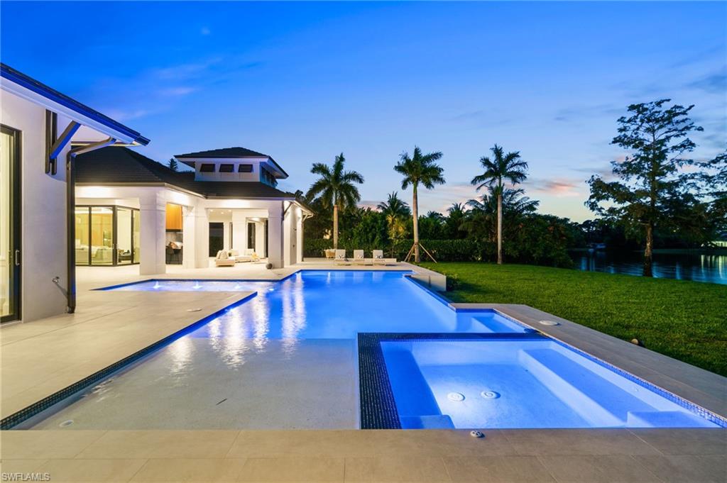 337 West Street Naples, FL 34108 - Photo 12 of 50 Pool at dusk with an in ground hot tub, a patio, and a lawn