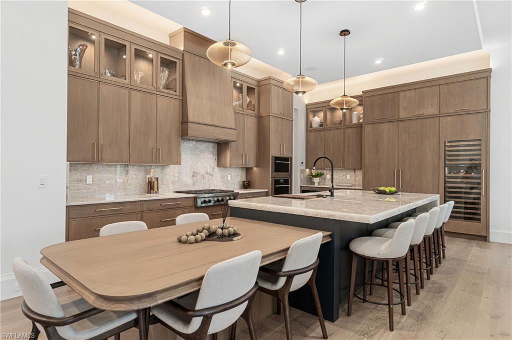337 West Street Naples, FL 34108 - Photo 18 of 50 Kitchen featuring decorative backsplash, pendant lighting, light hardwood / wood-style floors, and a kitchen island with sink