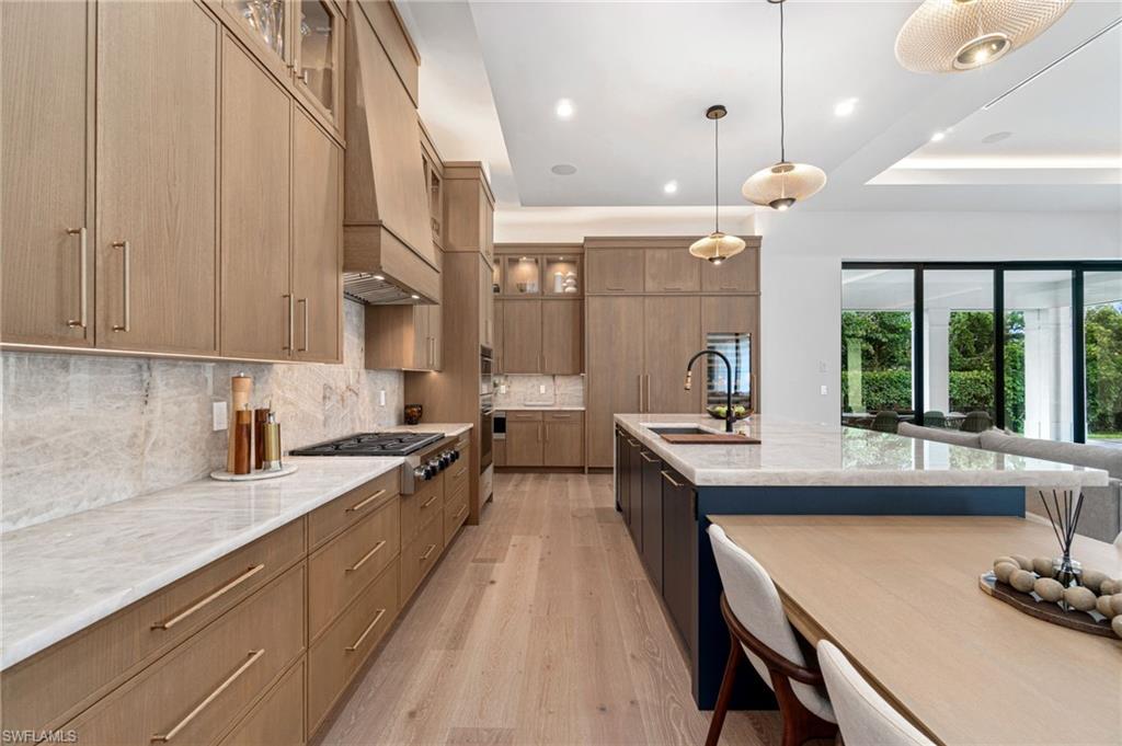 337 West Street Naples, FL 34108 - Photo 19 of 50 Kitchen featuring appliances with stainless steel finishes, tasteful backsplash, sink, light hardwood / wood-style floors, and custom range hood
