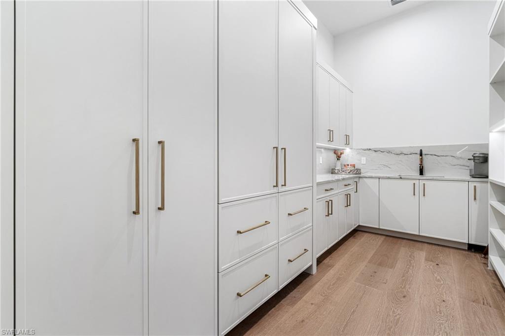 337 West Street Naples, FL 34108 - Photo 23 of 50 Kitchen featuring white cabinets, light stone counters, sink, and light wood-type flooring