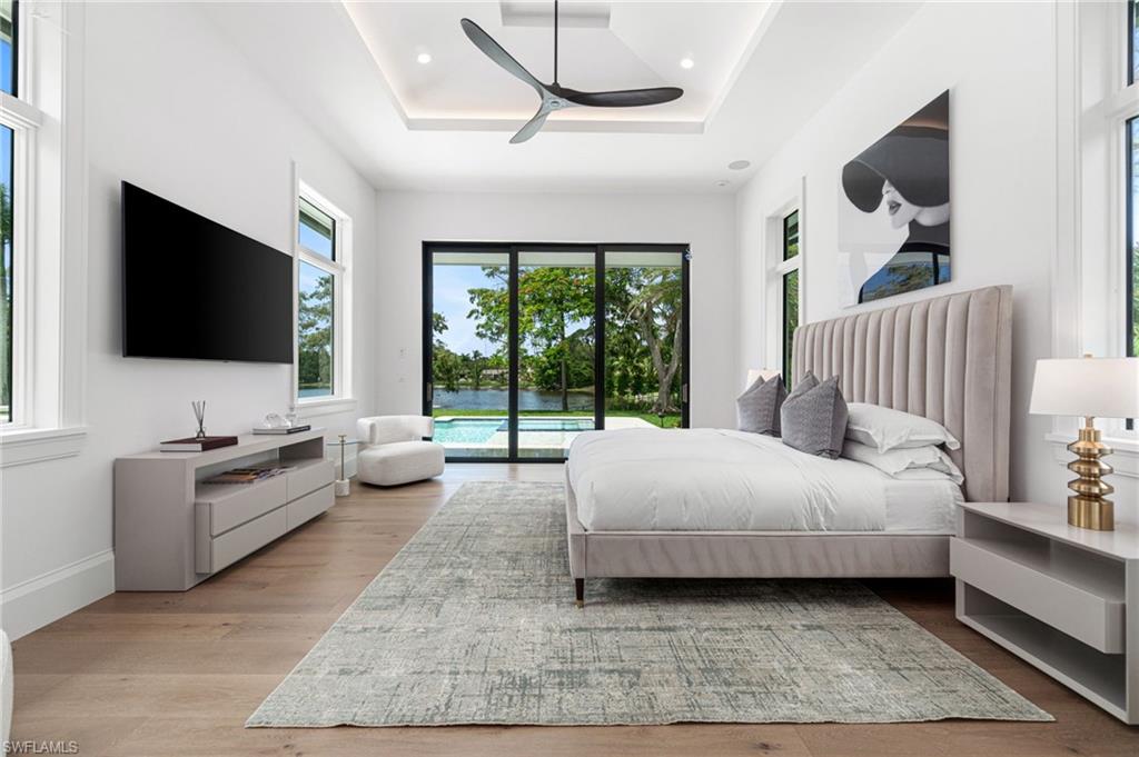 337 West Street Naples, FL 34108 - Photo 25 of 50 Bedroom with light hardwood / wood-style floors, ceiling fan, access to exterior, and a raised ceiling
