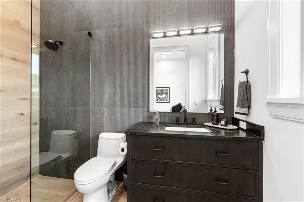 337 West Street Naples, FL 34108 - Photo 31 of 50 Bathroom featuring wood walls, toilet, and vanity