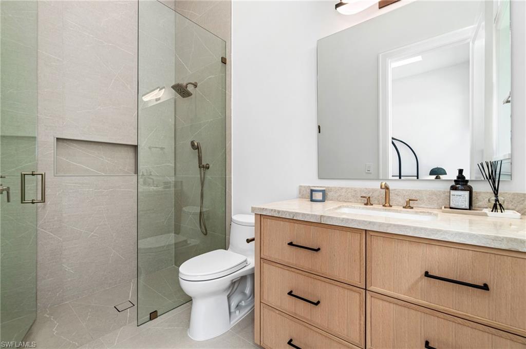 337 West Street Naples, FL 34108 - Photo 38 of 50 Bathroom featuring tile patterned flooring, toilet, vanity, and an enclosed shower