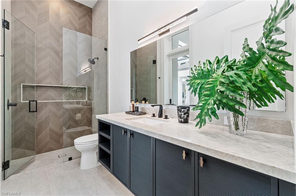 337 West Street Naples, FL 34108 - Photo 42 of 50 Bathroom featuring tile patterned floors, a shower with shower door, toilet, and vanity