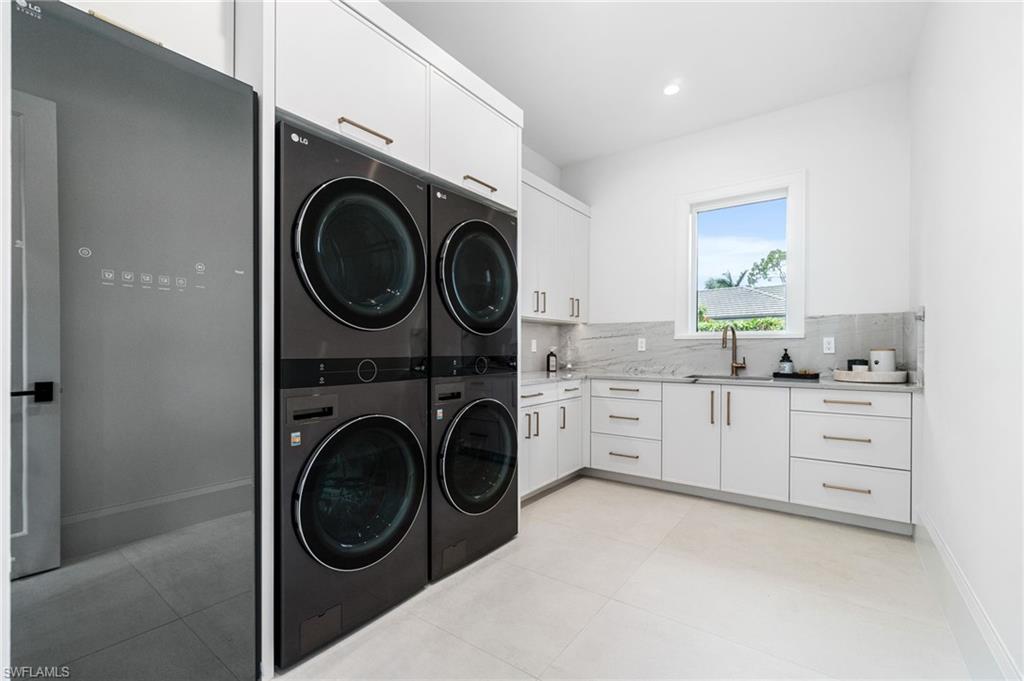 337 West Street Naples, FL 34108 - Photo 43 of 50 Laundry room featuring cabinets, stacked washer / dryer, sink, and light tile patterned floors