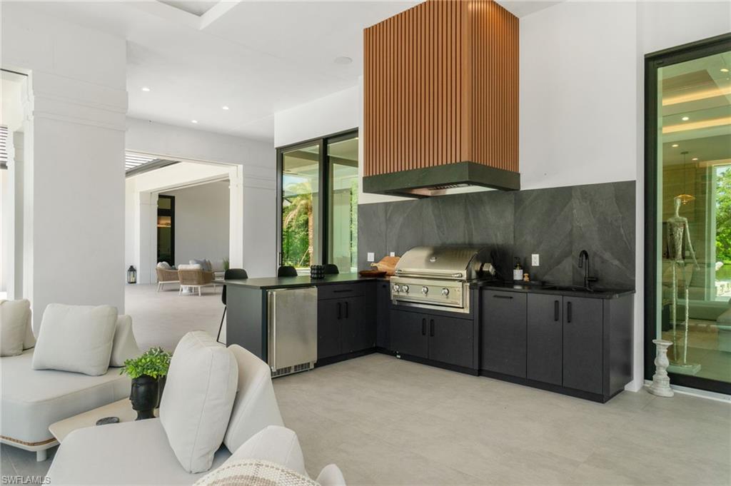 337 West Street Naples, FL 34108 - Photo 48 of 50 Kitchen with sink, fridge, decorative backsplash, and wall chimney range hood