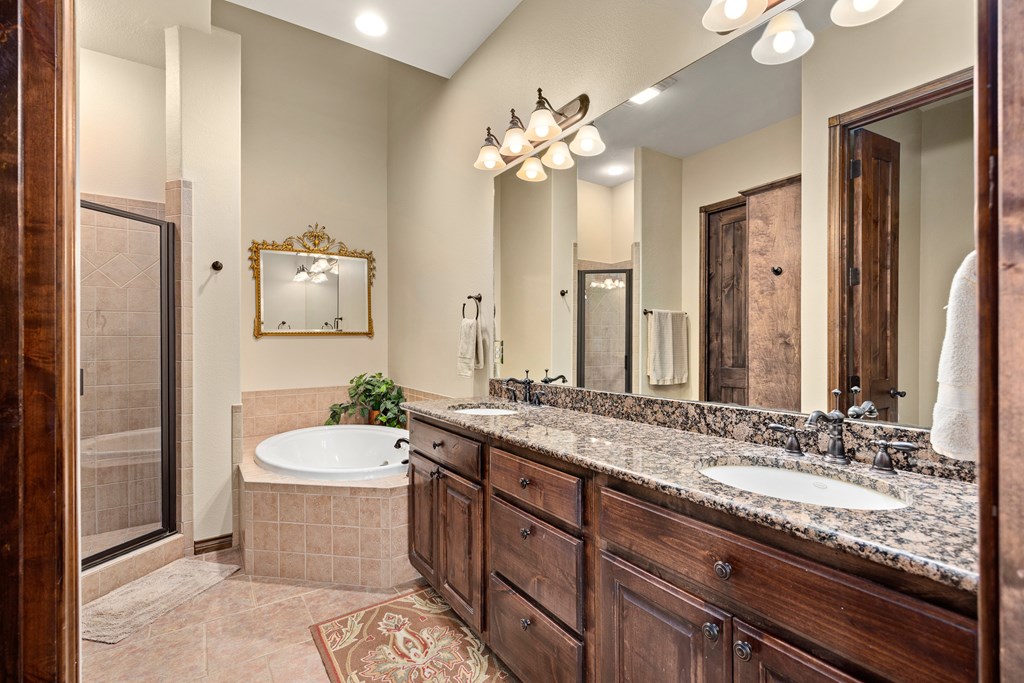3801-16 Club House Road Kerrville, TX 78028 - Photo 11 of 22 a bathroom with a granite countertop sink a toilet a mirror and shower
