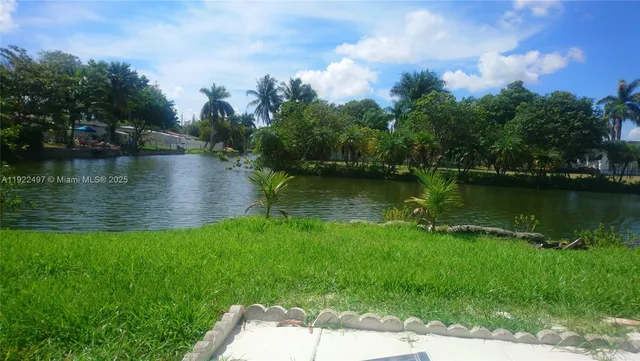 a view of a lake with a yard and large trees