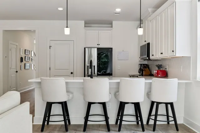 a kitchen with stainless steel appliances kitchen island granite countertop a table chairs and a refrigerator