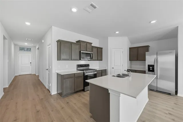 a kitchen with a sink a counter top space stainless steel appliances and cabinets