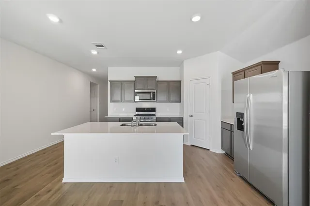 a large kitchen with stainless steel appliances a refrigerator sink and cabinets