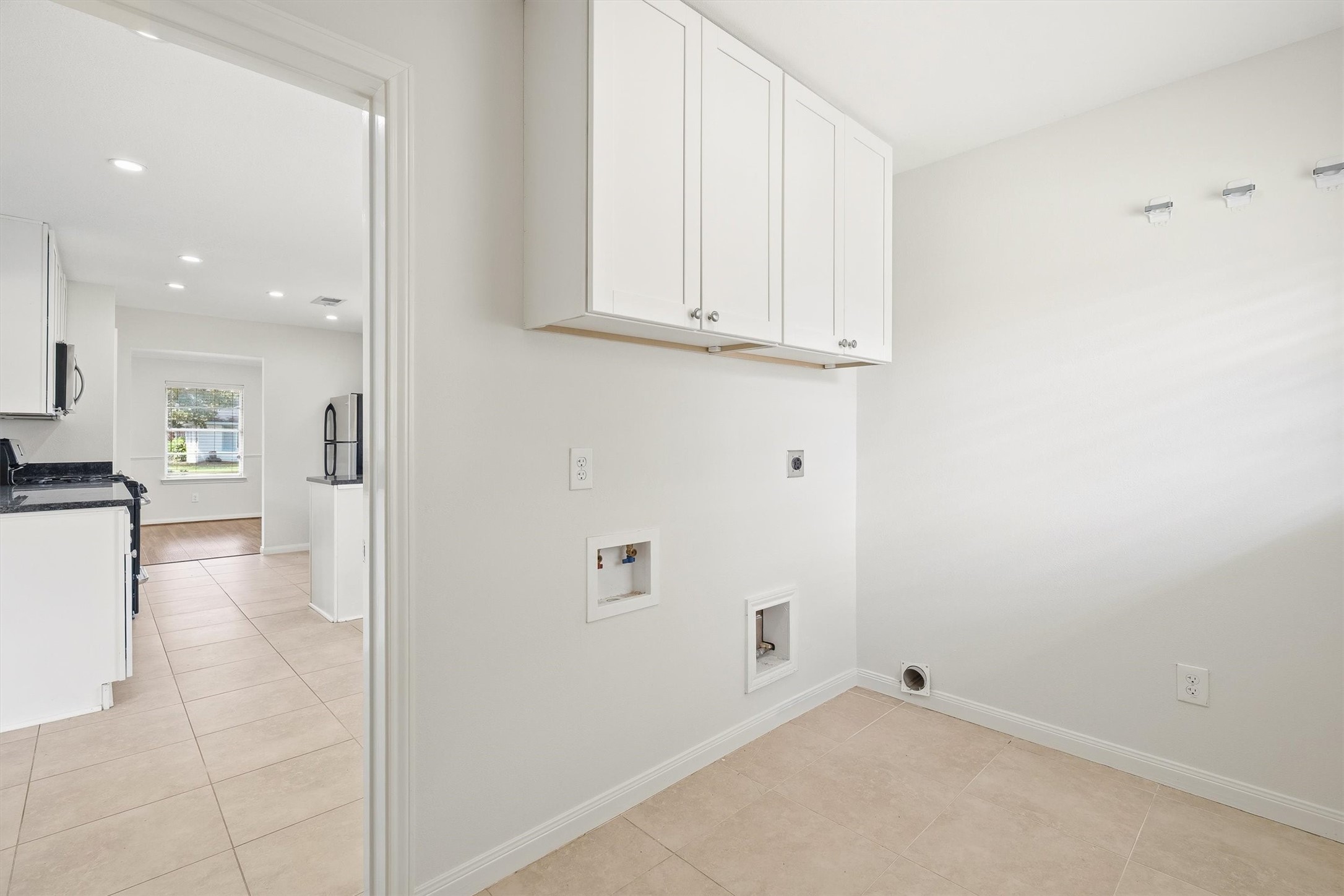 3331 Arbor Street Houston, TX 77004 - Photo 12 of 30 This photo shows a bright, tiled laundry area with white cabinetry and hookups for appliances.