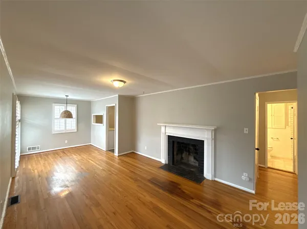 an empty room with wooden floor fireplace and windows