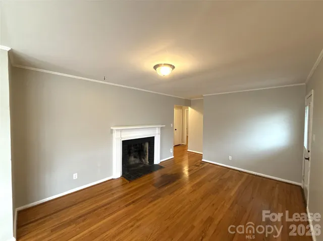 a view of empty room with wooden floor and fireplace