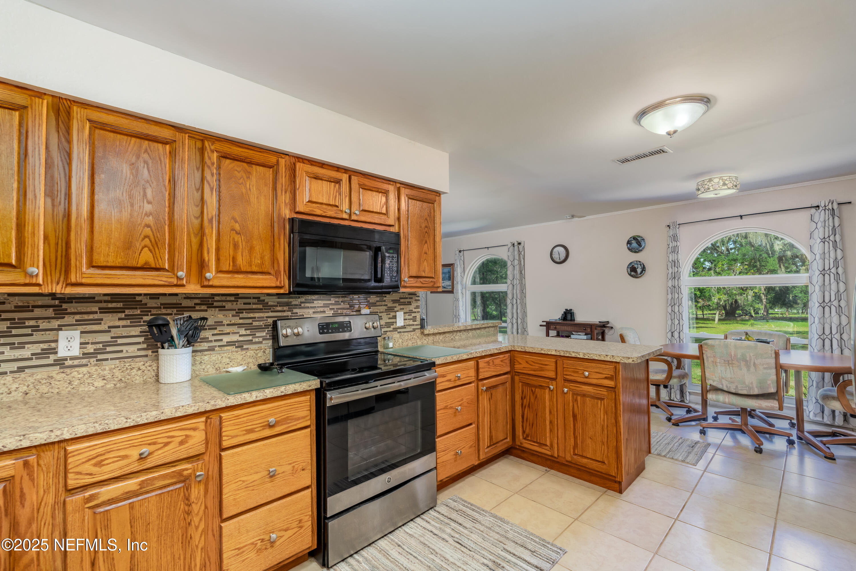 8048 County Line Road Melrose, FL 32666 - Photo 30 of 40 a kitchen with stainless steel appliances granite countertop a stove top oven a sink dishwasher and white cabinets with wooden floor