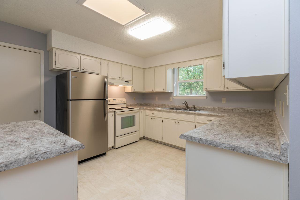 6130 Beasley Road Crestview, FL 32536 - Photo 4 of 28 a kitchen with granite countertop white cabinets and refrigerator