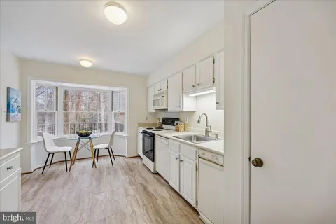 a kitchen with a table chairs a sink dishwasher refrigerator and cabinets
