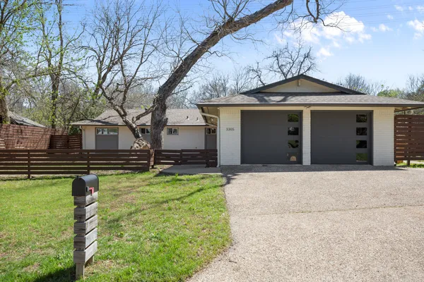 a front view of house with yard and trees in the background